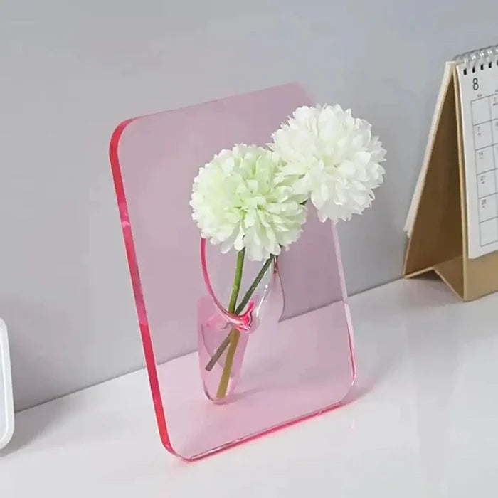 Acrylic Frame Vase in soft pink acrylic holding two white flowers, showcasing minimalist elegance and modern home interior decor with a floating floral effect.