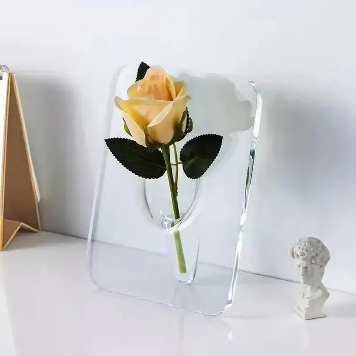 A clear Acrylic Frame Vase holding a single pale yellow rose with green leaves, showcasing minimalist elegance and modern home interior decor style.