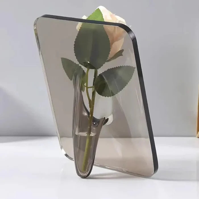 A sleek Acrylic Frame Vase in clear acrylic with a modern minimalist design, featuring a single pale pink flower appearing to float within the frame, perfect for personalized home interior decor.