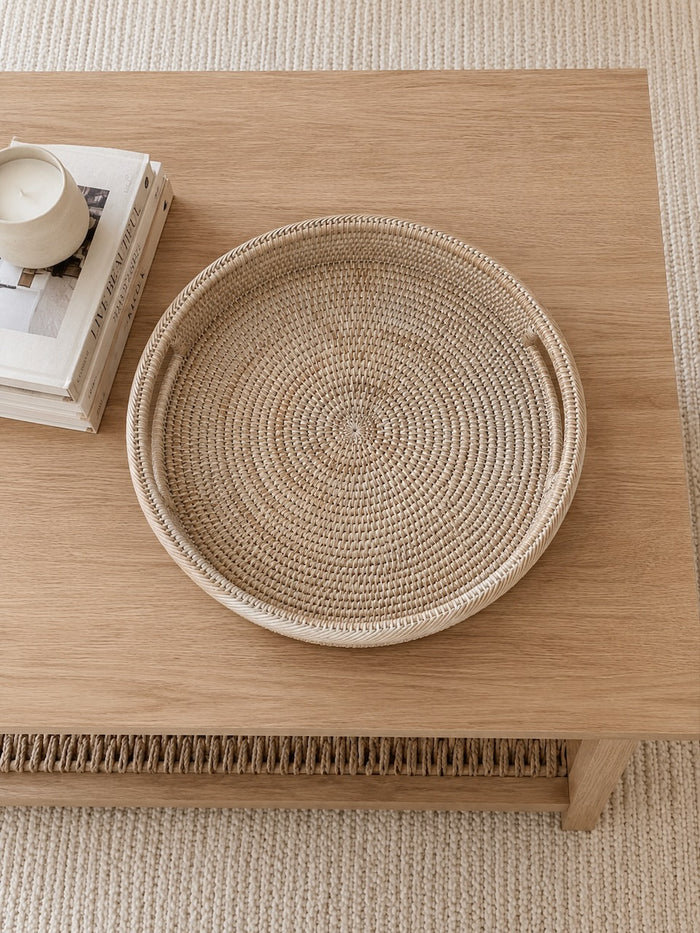 Alden rattan tray on a wooden coffee table with books and a candle