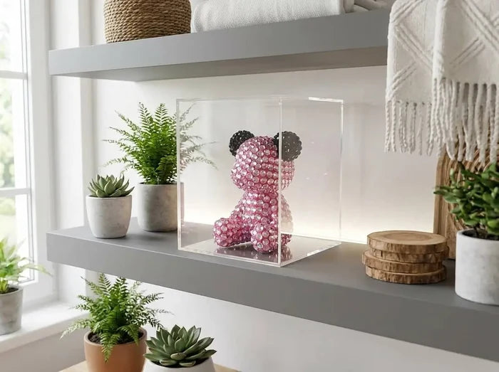 Pink crystal bear figurine in clear display box on modern shelf with plants and cozy décor