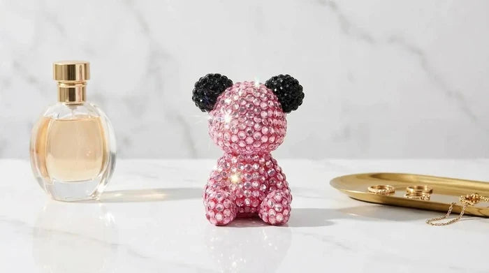 Pink crystal bear figurine with black ears, styled on marble with perfume and jewelry