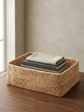Blair natural rattan shelf basket styled on wooden shelf with books and folded linen, rectangular woven storage basket for shelving organisation UK home interior