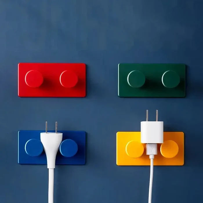 Block Key Hook in red, green, blue, and yellow mounted on a dark wall, holding white electrical plugs, combining functional home interior decor with playful, handmade customization.
