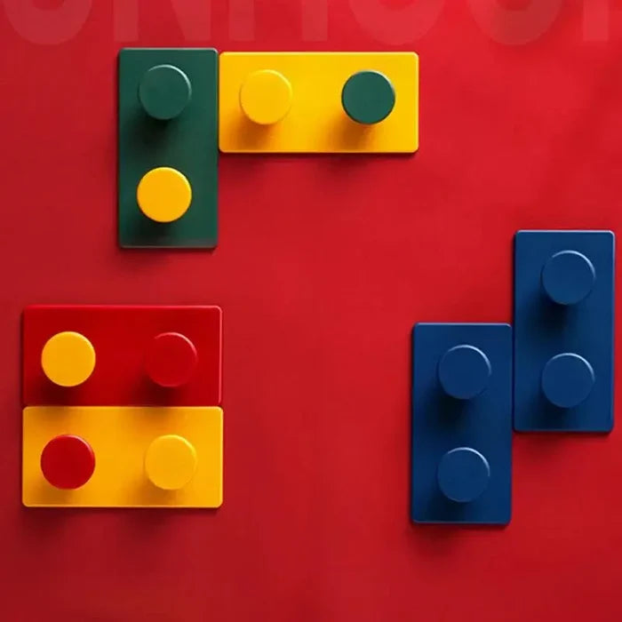 Brightly colored Block Key Hook sets in green, yellow, red, and blue arranged artistically on a bold red background, showcasing a playful, space-saving wall accessory.