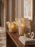 Decorative candles and vases on a wooden surface with a neutral color scheme.
