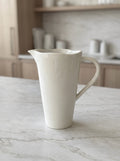 White ceramic jug on a marble surface with a kitchen background