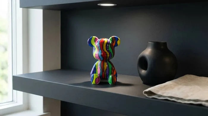Colorful striped bear figurine on modern shelf with black vase and natural linen