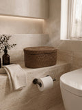 Bathroom with Jarra rattan basket toilet paper holder on a stone shelf.