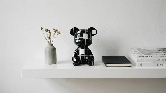 Black and white geometric bear figurine on shelf with dried flowers and books for modern home décor