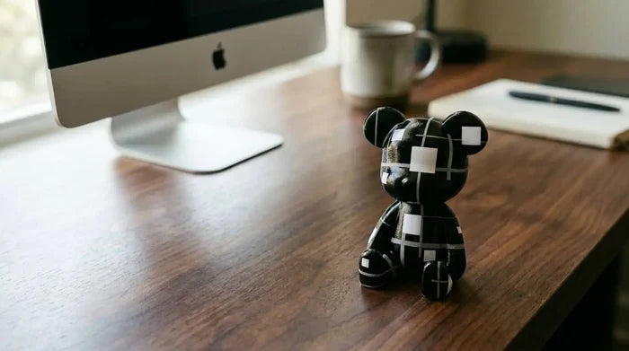 Black and white patterned bear figurine on wooden desk beside computer
