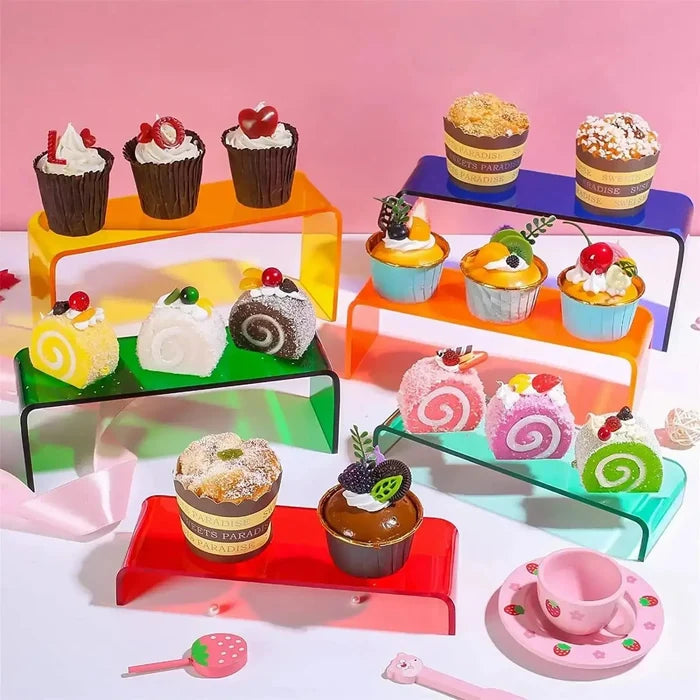 Colorful cupcakes and dessert rolls on vibrant acrylic stands with pink tea set accents