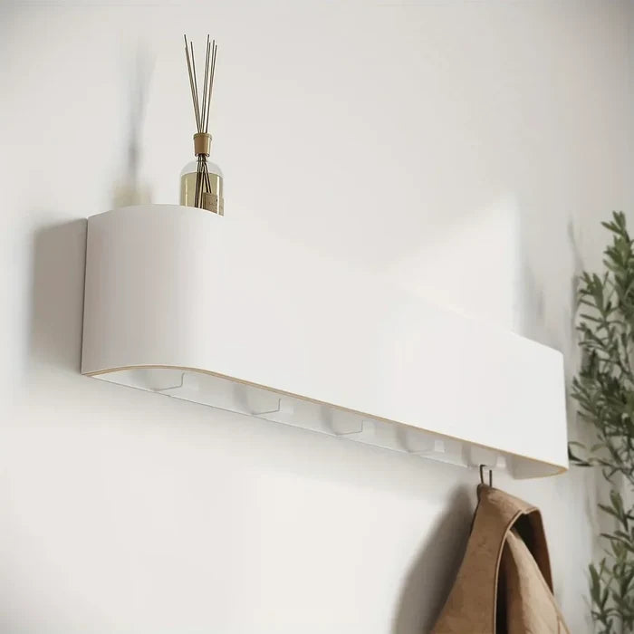 White wall-mounted shelf with hooks and a diffuser on a light gray wall.