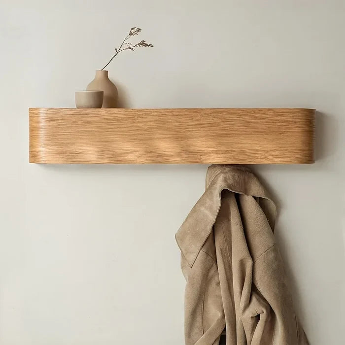 Wooden shelf with a beige coat and decorative vases on a light wall.